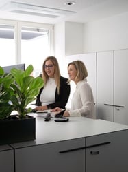 Zwei Mitarbeiterinnen arbeiten gemeinsam an einem Stehtisch am PC.