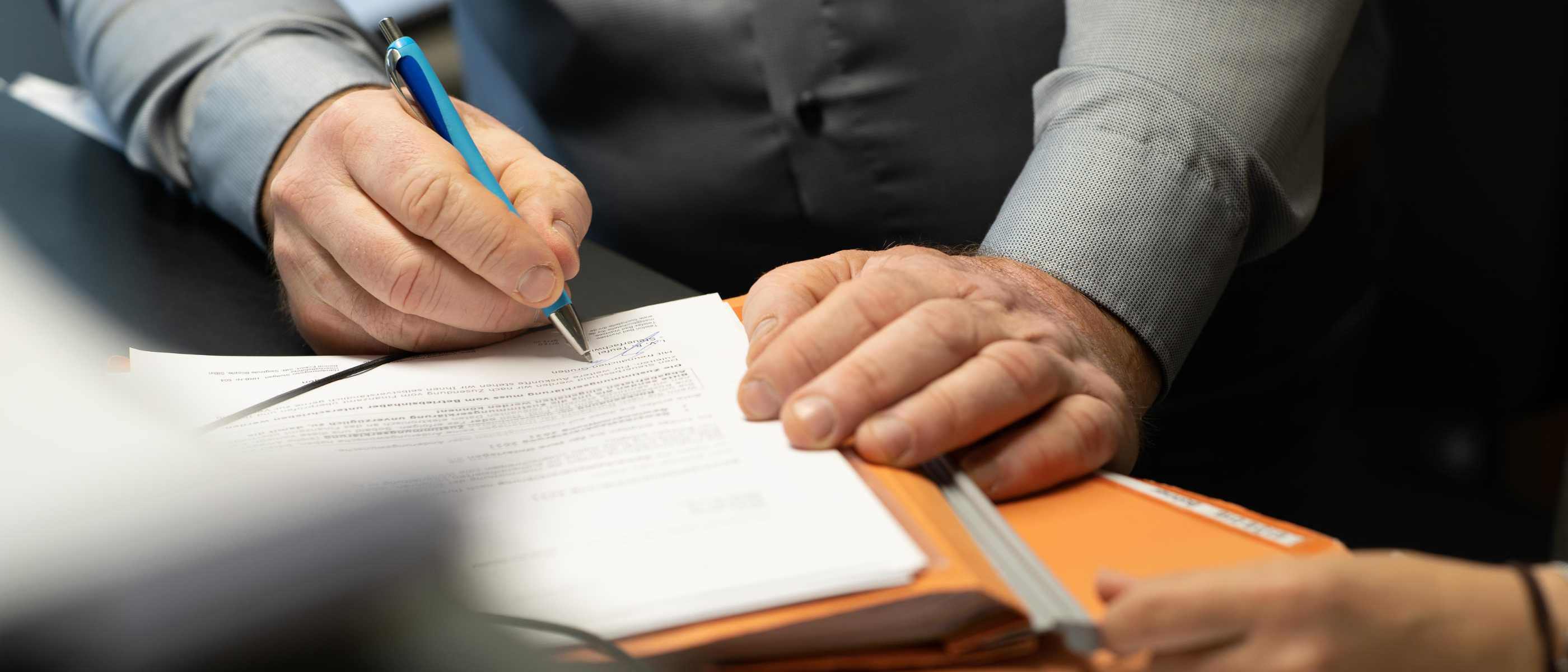 Person unterschreibt Vertragsunterlagen.