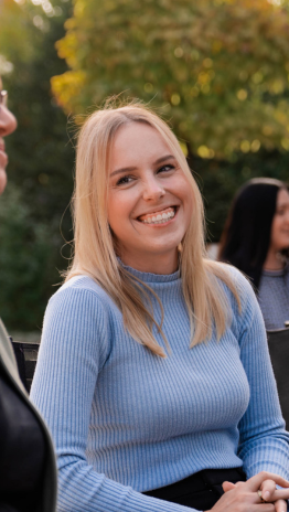 Trainee sitzt in der Mittagspause mit Kollegen und Kolleginnen am Tisch.