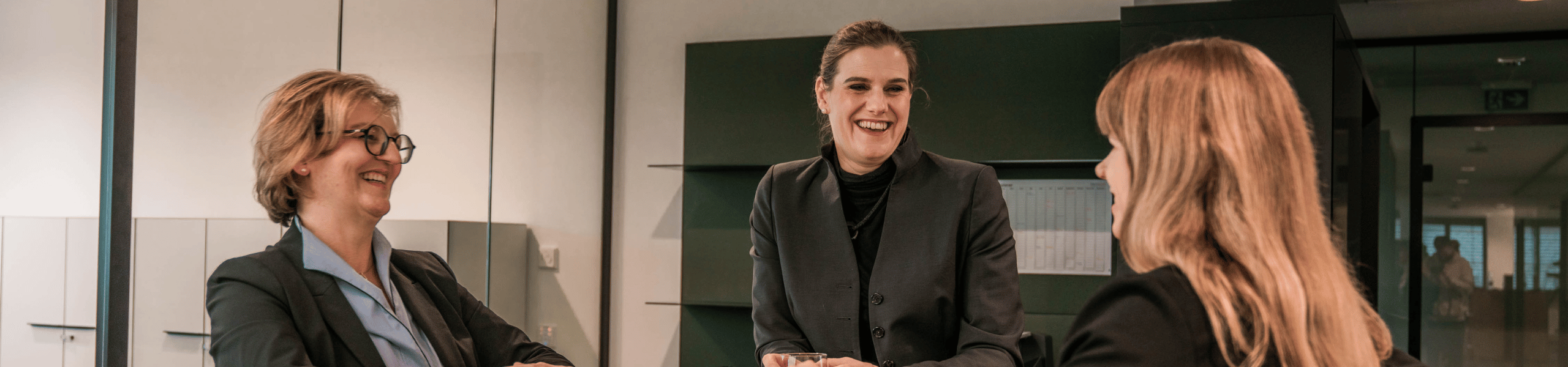 Mitarbeiterin, Personalleitung und Geschäftsführung stehen gemeinsam an einem Tisch in der Pause.