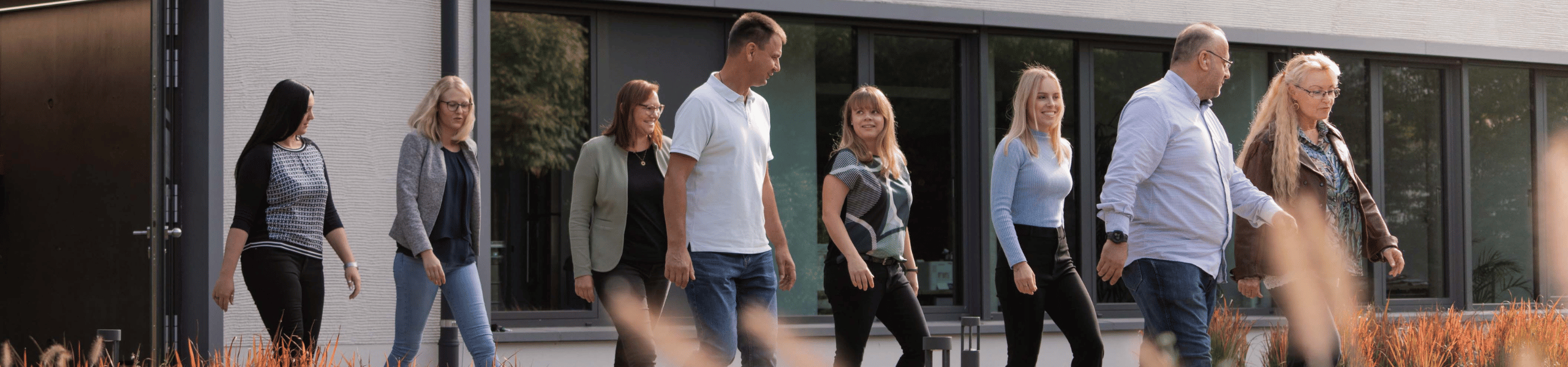 Mitarbeitende laufen gemeinsam in den Garten der Niederlassung Stuttgart Birkach.