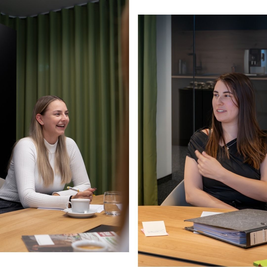 Zwei Azubis diskutieren mit einander im Meetingraum.