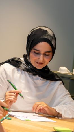 Auszubildende sitzt im Meetingraum und macht sich Notizen.