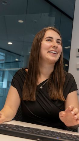 Studentin sitzt am Arbeitsplatz und tippt auf der Tastatur.