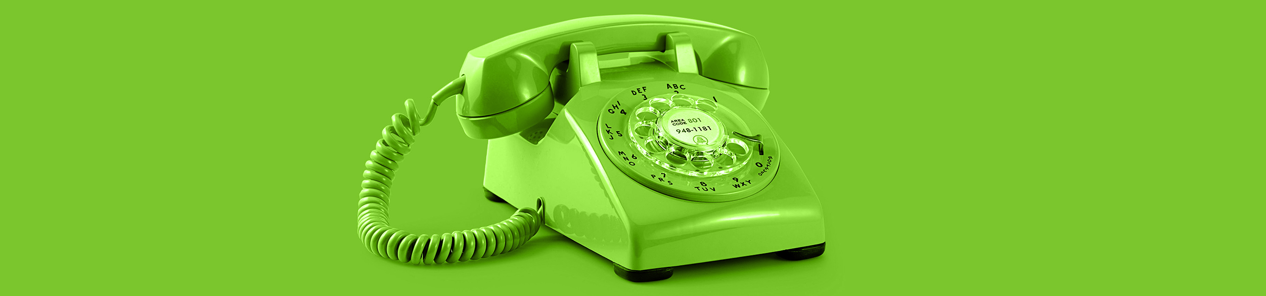 Grünes Telefon mit Wahlscheibe vor einem grünen Hintergrund